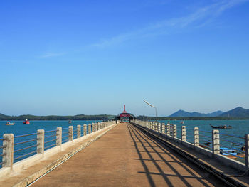 Pier over sea against clear blue sky
