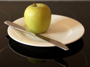 Close-up of granny smith apple on plate with knife