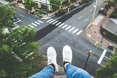 Low section of man walking on road in city