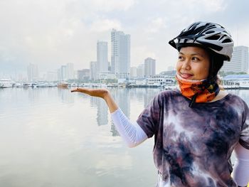 Young woman gesturing while standing against bay