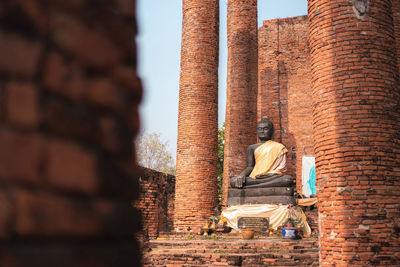 View of a buddha statue against brick wall