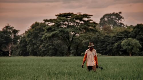 Man standing on field against trees