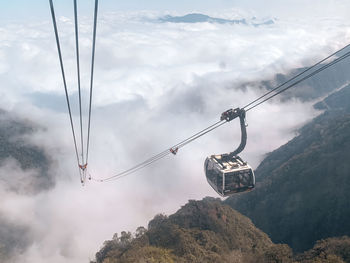 Low angle view of overhead cable cars against mountains