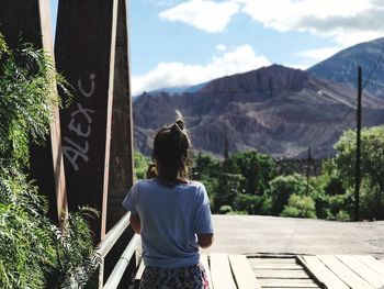 Rear view of man looking at mountains against sky