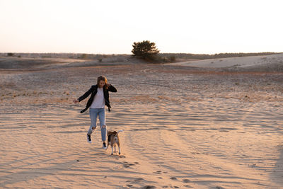 Rear view of woman walking on beach against clear sky