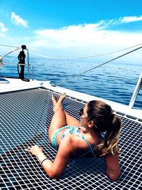 Woman with arms raised against sea against sky