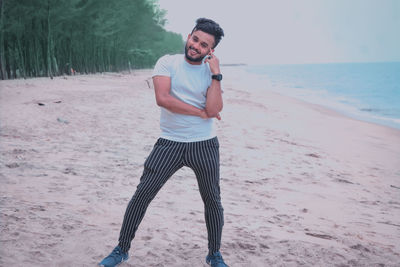 Full length of young man using mobile phone at beach