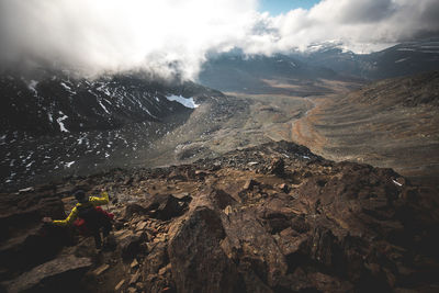 Man climbing on mountain against sky