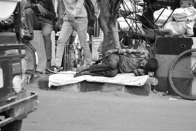 Low section of woman sleeping on sidewalk by street