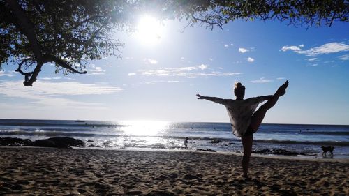 Man with arms outstretched on beach against sky