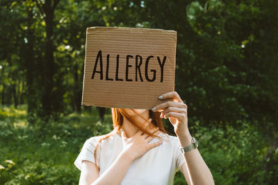 Woman holding text on cardboard outdoors