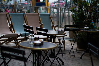 Empty chairs and tables at sidewalk cafe against building