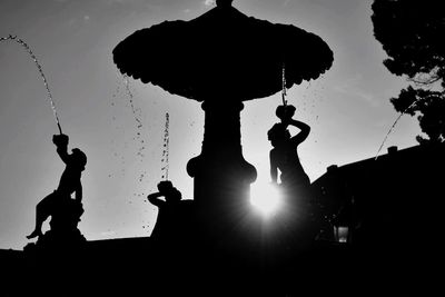 Low angle view of silhouette statue against sky