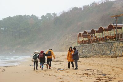 Rear view of people walking on beach