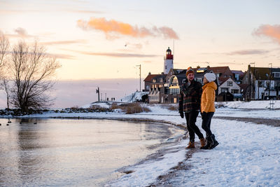 Rear view of man standing on snow against sky during sunset