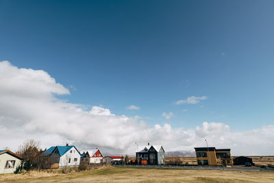 Houses by buildings against blue sky