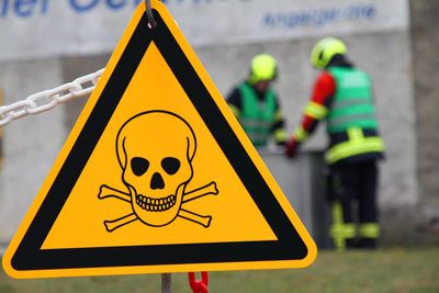 Close-up of warning sign against workers in background at construction site