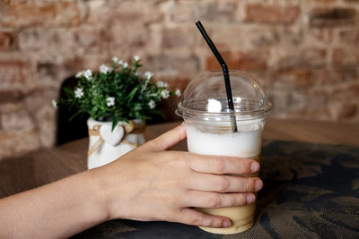 Close-up of a young woman's hand takes a cup of cold coffee from a table in a cafe. cold drinks. 