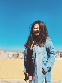 Young woman standing against blue sky