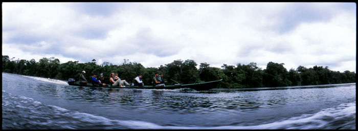 People in river against cloudy sky