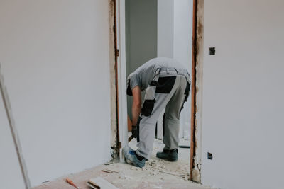 A man working with a crowbar in a doorway.