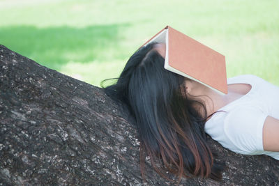 Midsection of woman reading book against plants