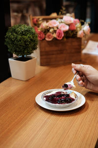 Close-up of hand with flowers in plate on table