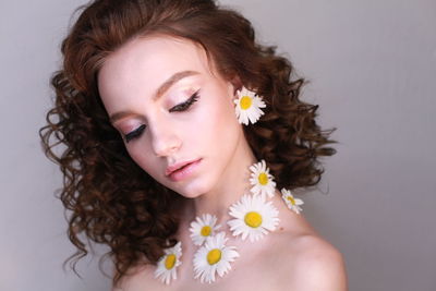 Close-up of teenage girl wearing flowers against wall