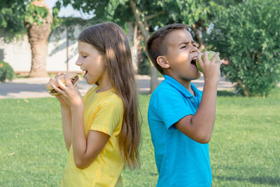 Schoolchildren eat hamburgers in the park. lunch after school.