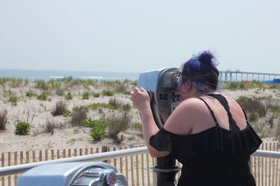 Rear view of woman photographing on beach