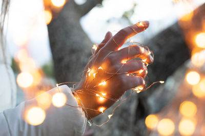 Close-up of hand holding illuminated christmas lights