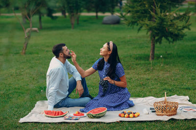 Full length of man and woman having food on field
