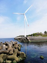 Traditional windmill on shore against sky