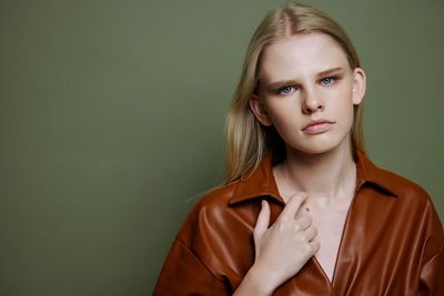 Portrait of young woman against green background