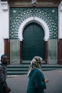 Rear view of woman standing against door of building