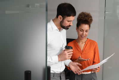 Young woman using digital tablet while standing in office