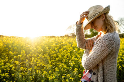 Portrait of a girl with a straw hat in a rapeseed field at sunset