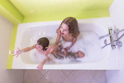 High angle view of happy siblings playing in bathtub