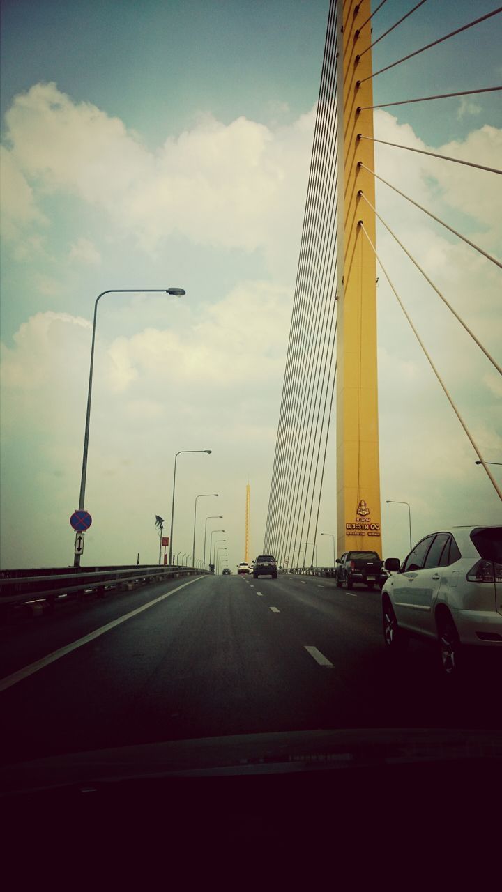 transportation, mode of transport, road, the way forward, sky, road marking, car, cloud - sky, land vehicle, street light, travel, diminishing perspective, on the move, vanishing point, street, cloud, no people, cloudy, journey, connection