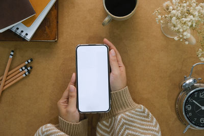 High angle view of woman using digital tablet and mobile phone and smart phones on table