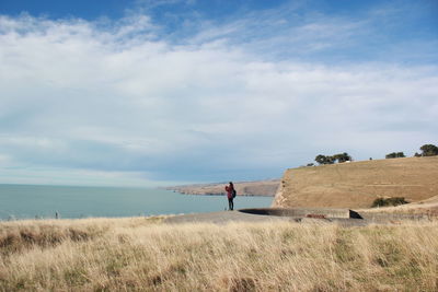 Man standing on shore by sea against sky
