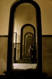 Reflection of young woman photographing with mobile phone on mirror