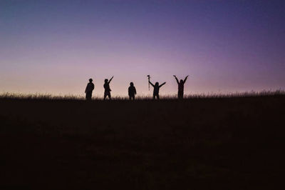 Silhouette people standing on field against sky during sunset