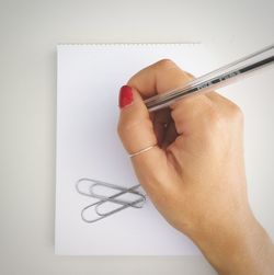 Close-up of hand writing on blank paper with pen against white background