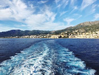 Scenic view of sea by mountains against blue sky