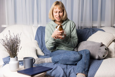 Portrait of young woman using mobile phone while sitting on bed at home