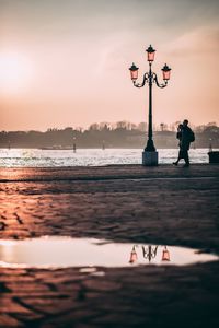 Women standing on beach against sky during sunset