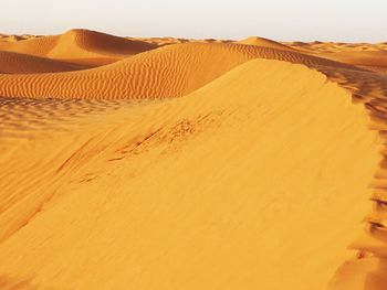 Sand dunes in desert against clear sky