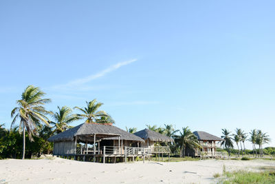 Stilt houses at beach against sky