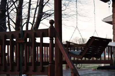 Wooden swing at patio against sky